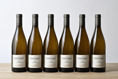 six bottles of white wine lined up on a wooden table