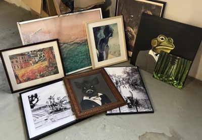 de nombreux tableaux encadrés posés par terre à côté d'un vase