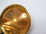 gros plan d'une montre de poche en or sur une surface blanche