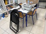 une table avec des chaises et un ordinateur portable posé dessus, dans une pièce