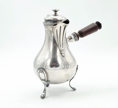 une cafetière ancienne en argent avec une poignée en bois sur un support