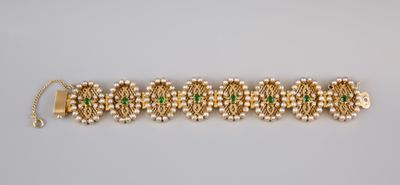 a gold bracelet with green stones and pearls