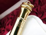 a small gold object in a white box on a red blanket