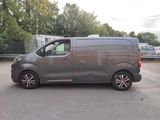 grey van parked in a parking lot with trees in the background