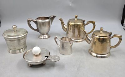 cinq théières en argent et une théière posées sur une table