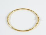 gros plan d'un bracelet en or sur une surface blanche