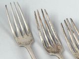 three forks and a knife are sitting on a white surface