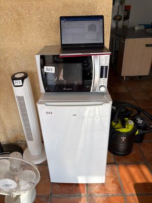 un petit réfrigérateur et un micro-ondes posés sur un sol carrelé