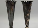 two silver vases sitting next to each other on a table