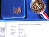 a silver coin in a blue box with a red, white, and blue ribbon