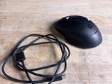 une souris noire et un cordon noir posés sur une table en bois