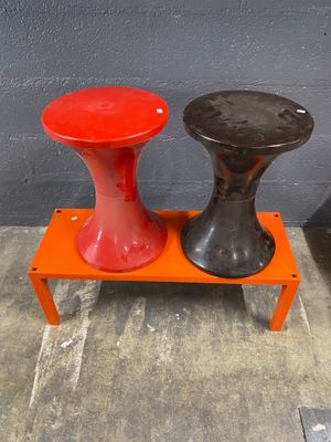 pair of red and black stools sitting on top of a small orange table