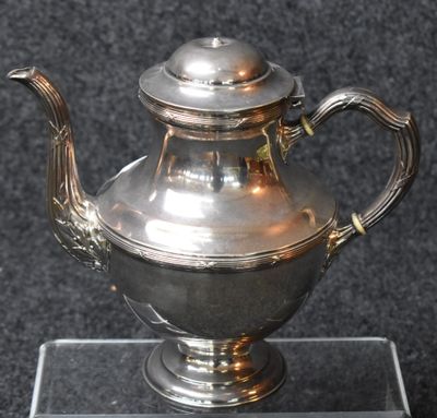 a silver tea pot sitting on a glass stand