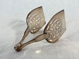 pair of antique silver plated serving utensils on a white cloth