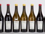 six bouteilles de vin alignées sur une surface blanche