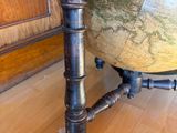 a table with a globe on top of it on a hard wood floor
