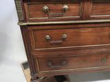 a wooden chest of drawers with brass hardware on top of it