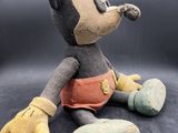 a close up of a stuffed mickey mouse sitting on a black surface
