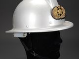 white hard hat on a mannequin head with a gold coin on it