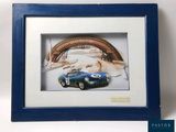 photo encadrée d'une voiture de sport bleue, dans un cadre bleu, sur fond blanc