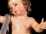 a statue of a baby holding a shoe on a black background
