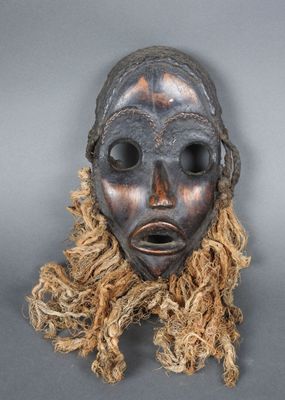 un gros plan sur un masque en bois aux longs cheveux