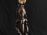 une sculpture africaine représentant une femme avec un oiseau sur la tête