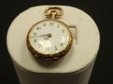 a gold pocket watch sitting on top of a white pedestal