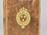 an old book with a gold emblem on it sitting on top of a table