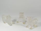 three white glass figurines of cats on a white surface