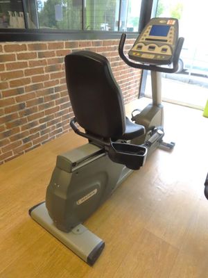 a stationary exercise bike in a gym room with a monitor on the wall