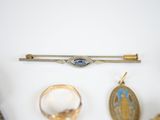 a gold broocht, a ring, and a broocht on a white surface