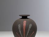 une image représentant un vase noir orné d'un motif rouge