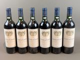 six bottles of wine are lined up in a row on a table