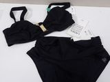 black bikini set with matching bra and panties on a white bed