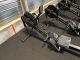 row of rowing machines in a gym with a wall in the background
