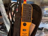 someone is holding a multimeter in their hand in a garage