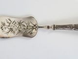 a silver spoon with a design on it sitting on a white surface