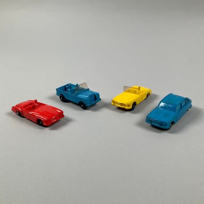 four toy cars are lined up in a row on a white surface
