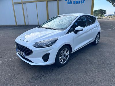 une Ford Fiesta blanche garée devant un immeuble