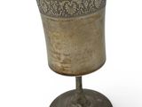 a silver cup sitting on a stand on a white surface