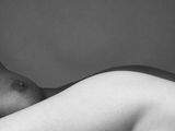 photographie en noir et blanc d'un homme nu allongé sur un lit