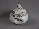 a white vase with a bird on it on a gray surface