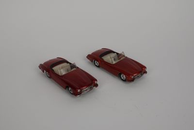 deux petites voitures rouges posées sur une surface blanche