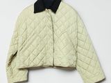 une veste blanche à col noir suspendue à un cintre