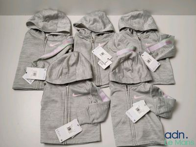 Quatre paires de vêtements pour bébé sont posées sur une table, avec leurs étiquettes encore attachées.