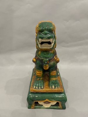 green and gold foo foo statue on a small table