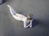 a small figurine of a woman laying on the ground