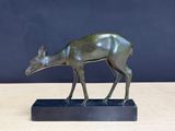 une image représentant une statue en bronze d'un cerf posée sur un socle noir