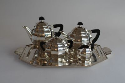 a silver tea set on a tray on a white table